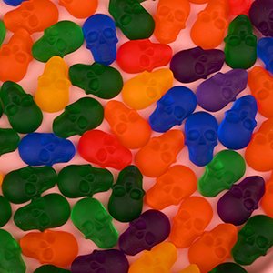 Assorted colorful skull-shaped gummies and chocolates filling the frame, close-up overhead view.