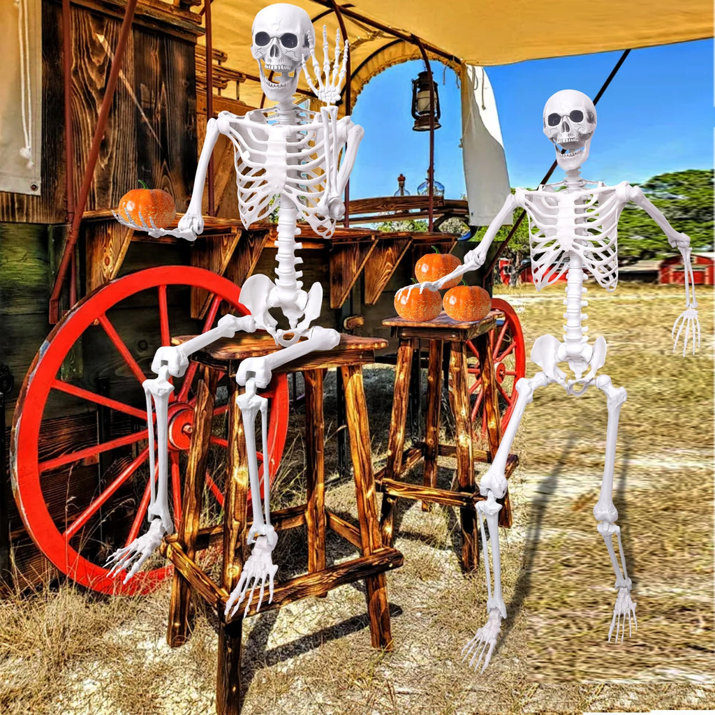 Two posable skeletons and artificial pumpkins sit on wooden stools next to a rustic wagon wheel and wagon.
