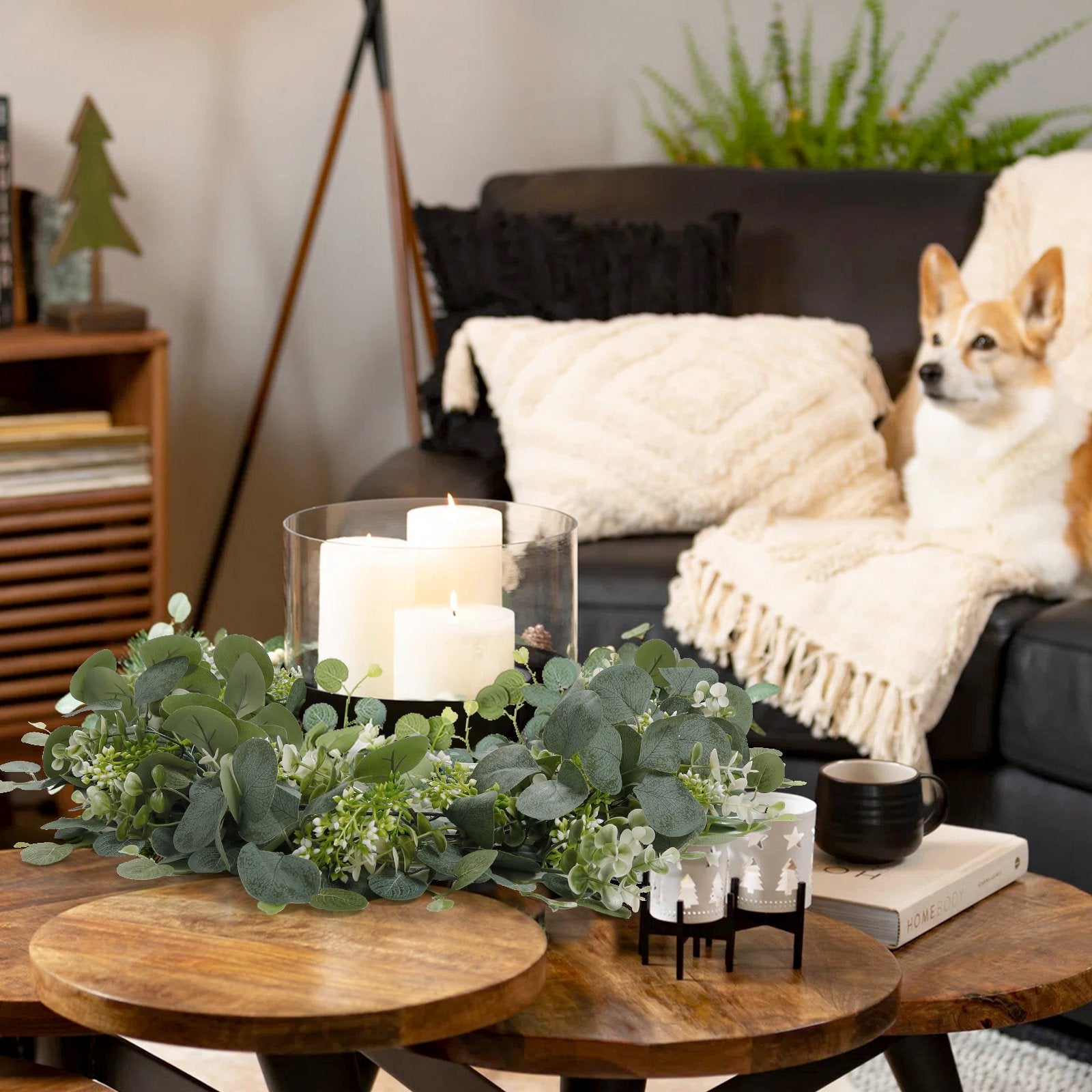 Faux eucalyptus garland with white berries arranged on a coffee table with candles and a dog on a couch in the background.