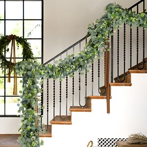 Faux eucalyptus garland with silver dollar leaves and small white flowers draped on a staircase railing