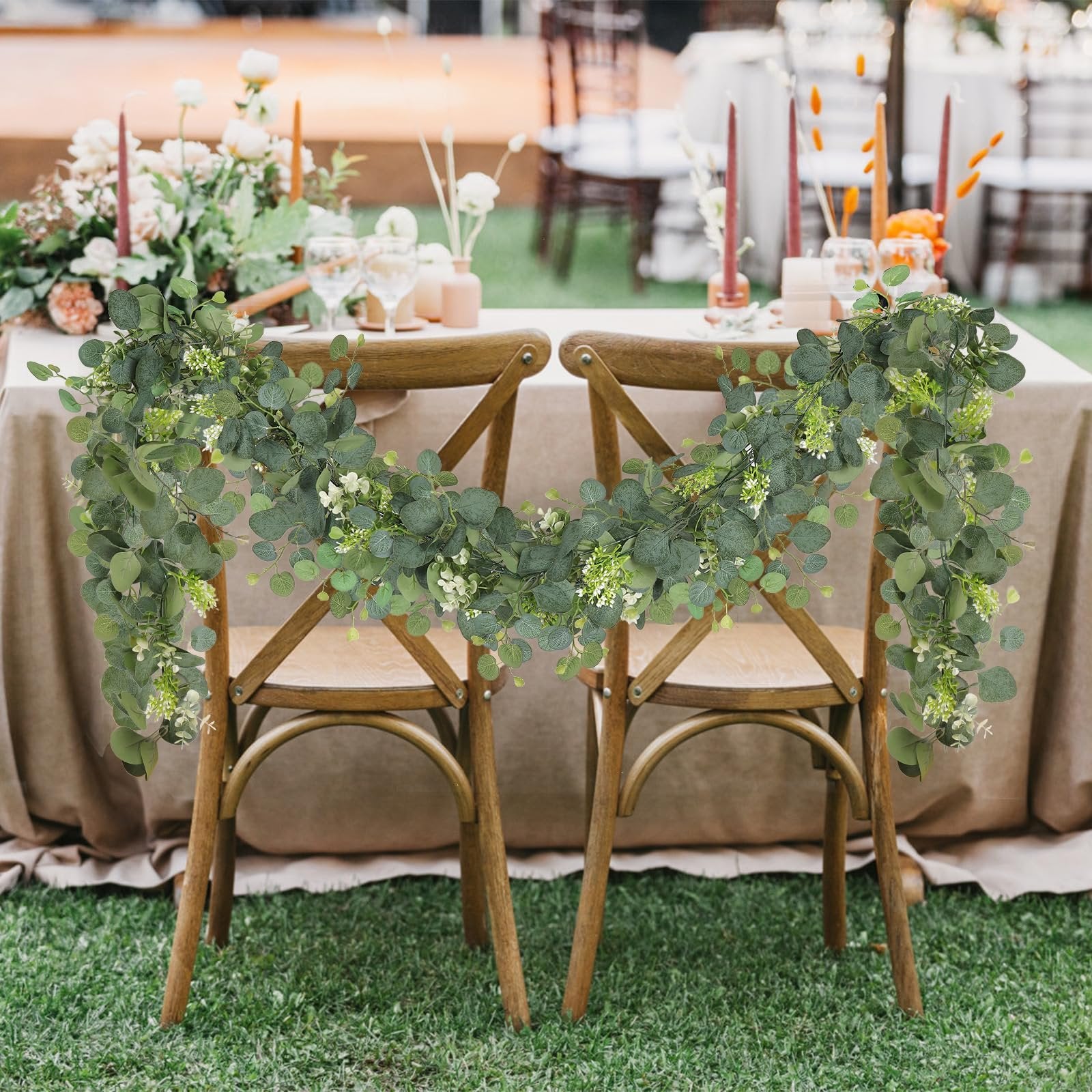 Faux eucalyptus garland draped over two wooden chairs at a table setting