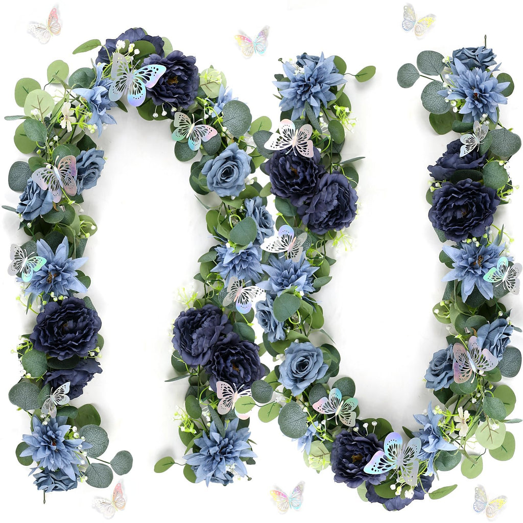 Artificial eucalyptus garland with navy blue flowers and silver butterflies arranged in a curve on a white background.
