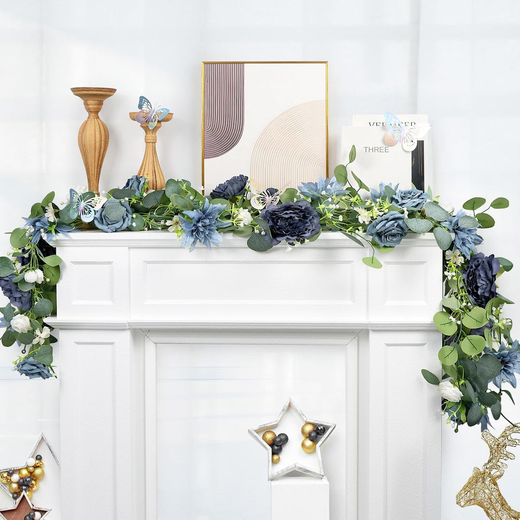 Artificial eucalyptus garland with navy blue flowers and silver butterflies draped over a white fireplace mantel.