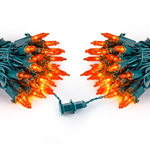 Two bundles of orange mini string lights with green wire on a white background, showing the plug end.