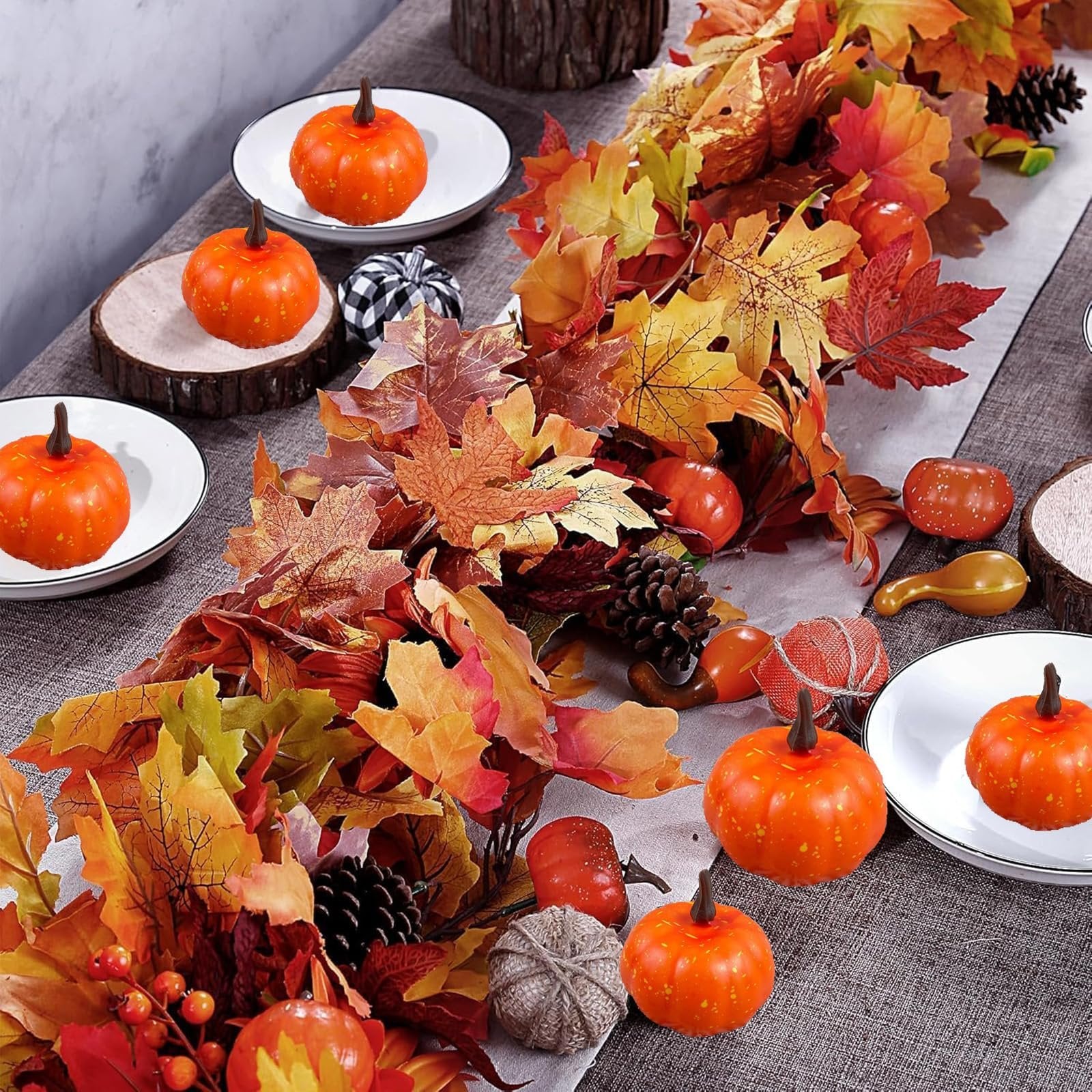Autumn maple leaf garland with pumpkins and pinecones arranged on a table setting.