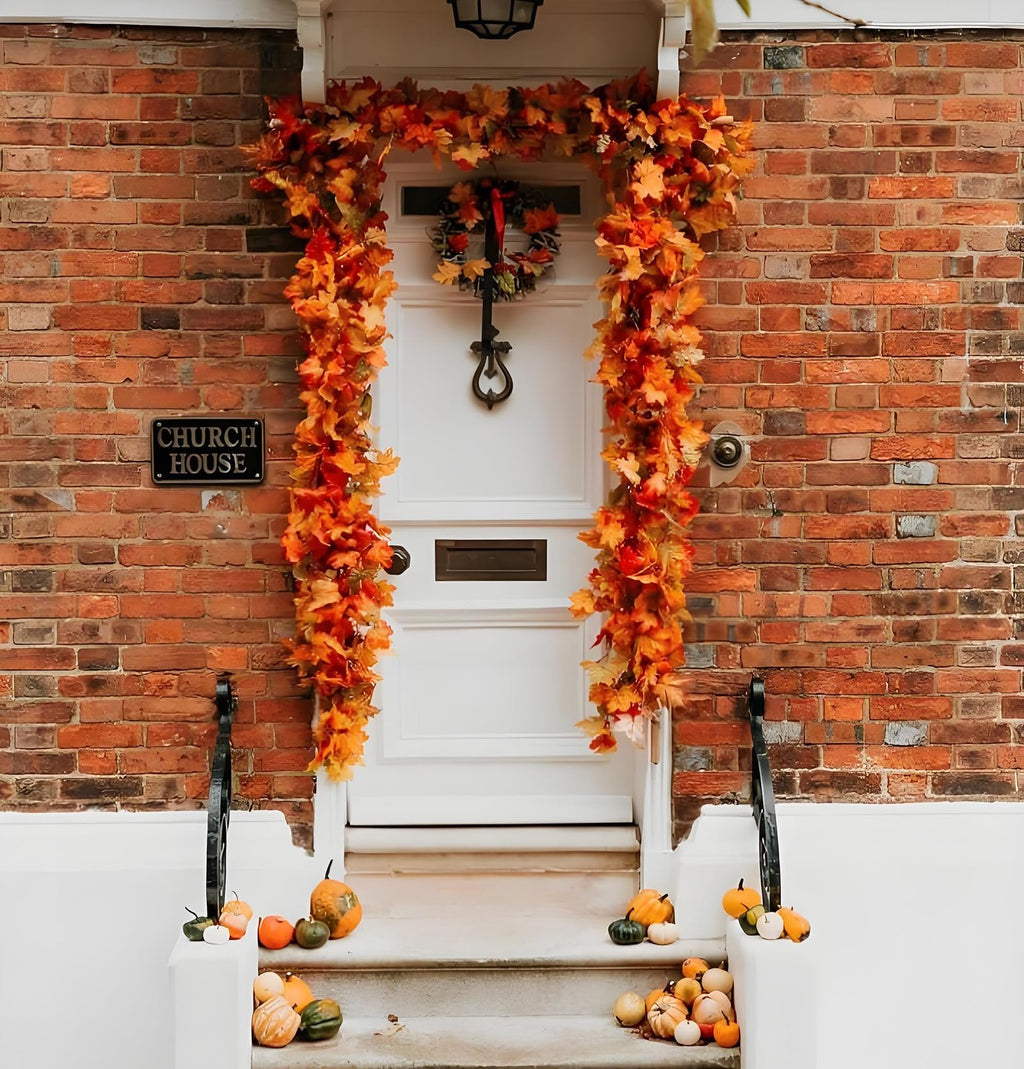 Front door decorated with autumn leaf garlands and pumpkins on the steps