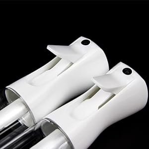 Two white continuous mist spray bottles with clear glass reservoirs against a black background.