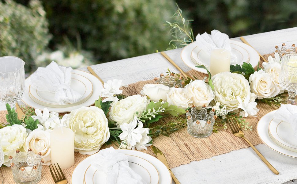 Table setting with white silk peony flower garland, candles, and gold cutlery.
