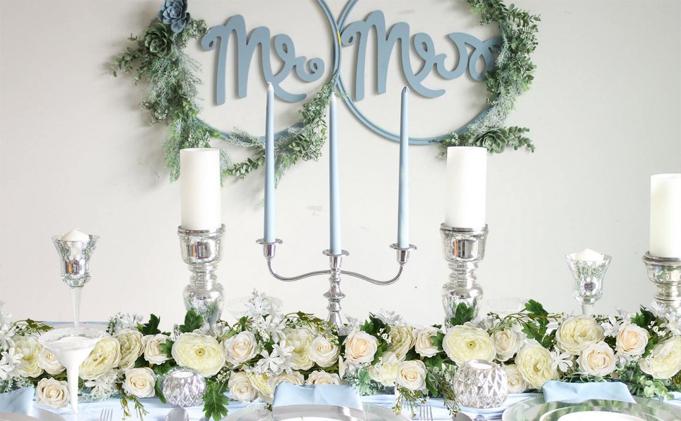 Wedding table setting with white floral garland, silver candelabras, and 'Mr & Mrs' sign.