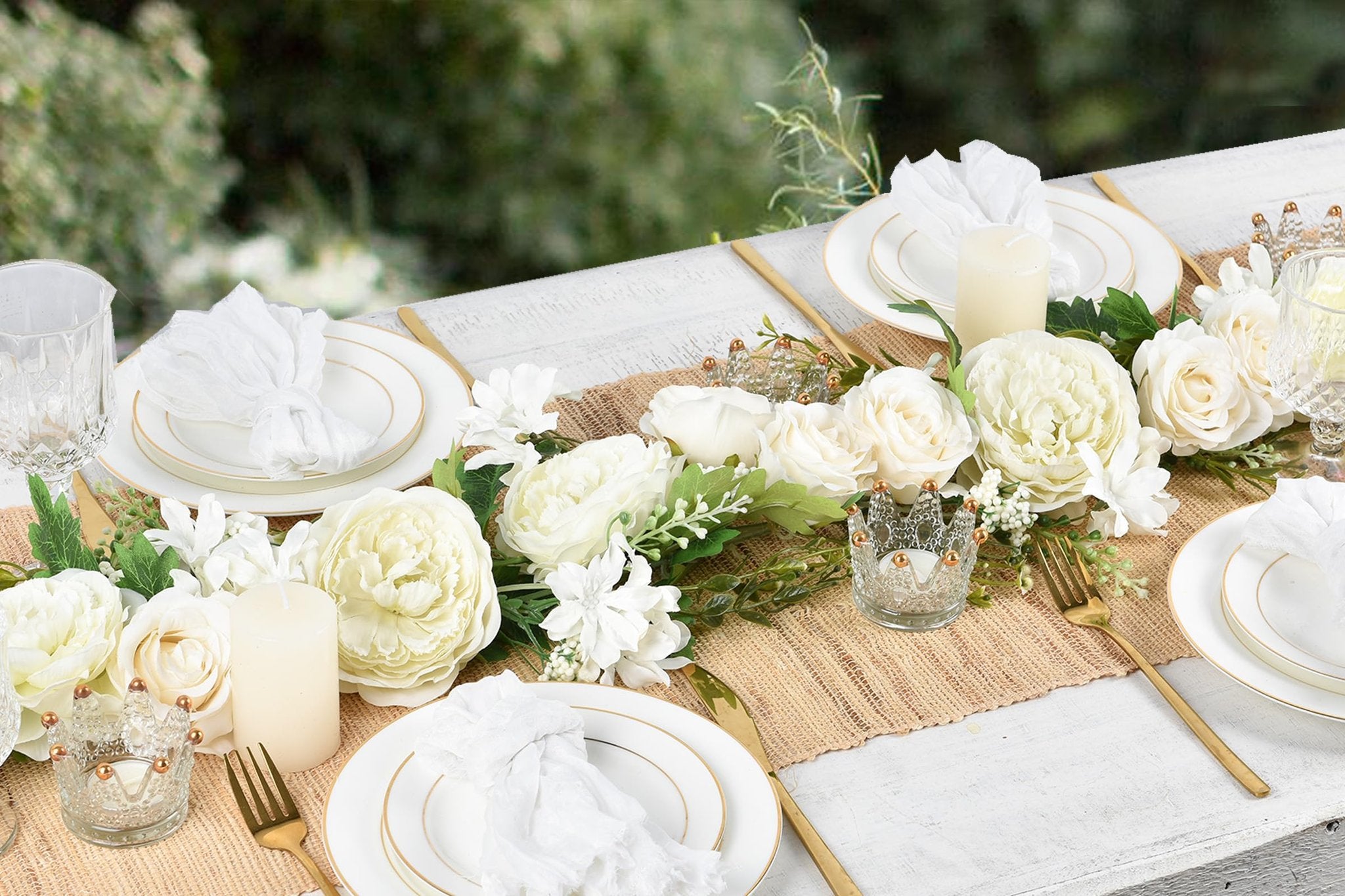Table setting with white silk peony flower garland, candles, and gold cutlery