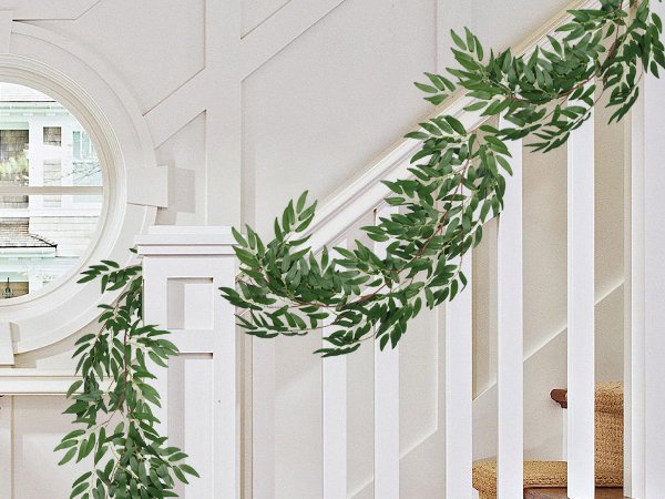 Artificial willow vine garland with green leaves draped over a white staircase railing