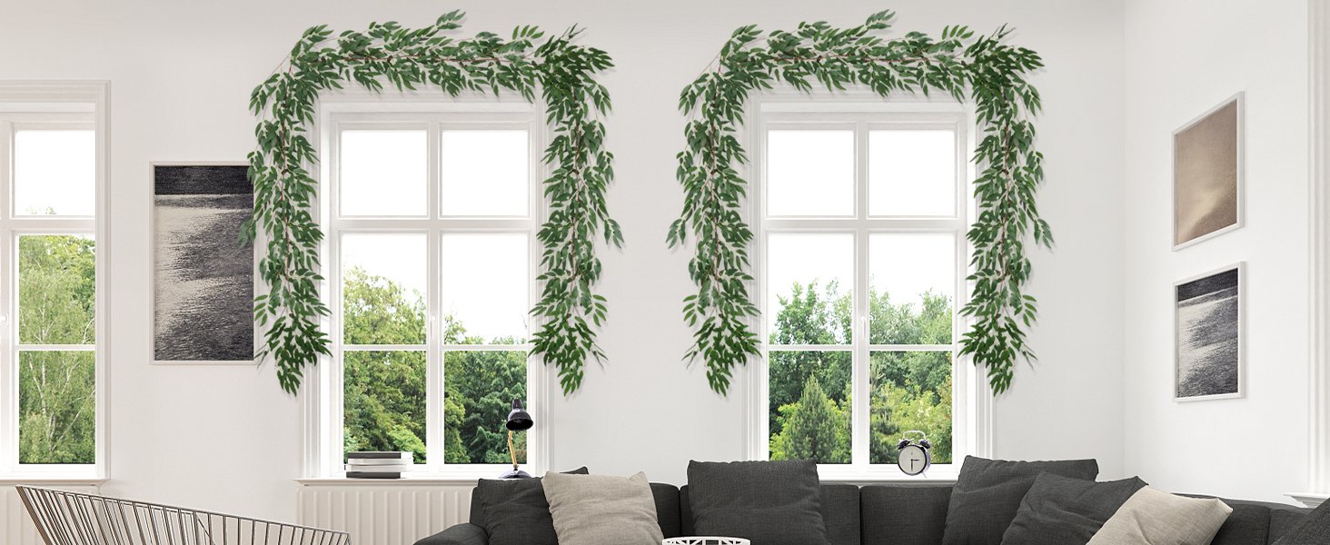 Two artificial willow vine garlands with green leaves draped over windows in a living room setting.