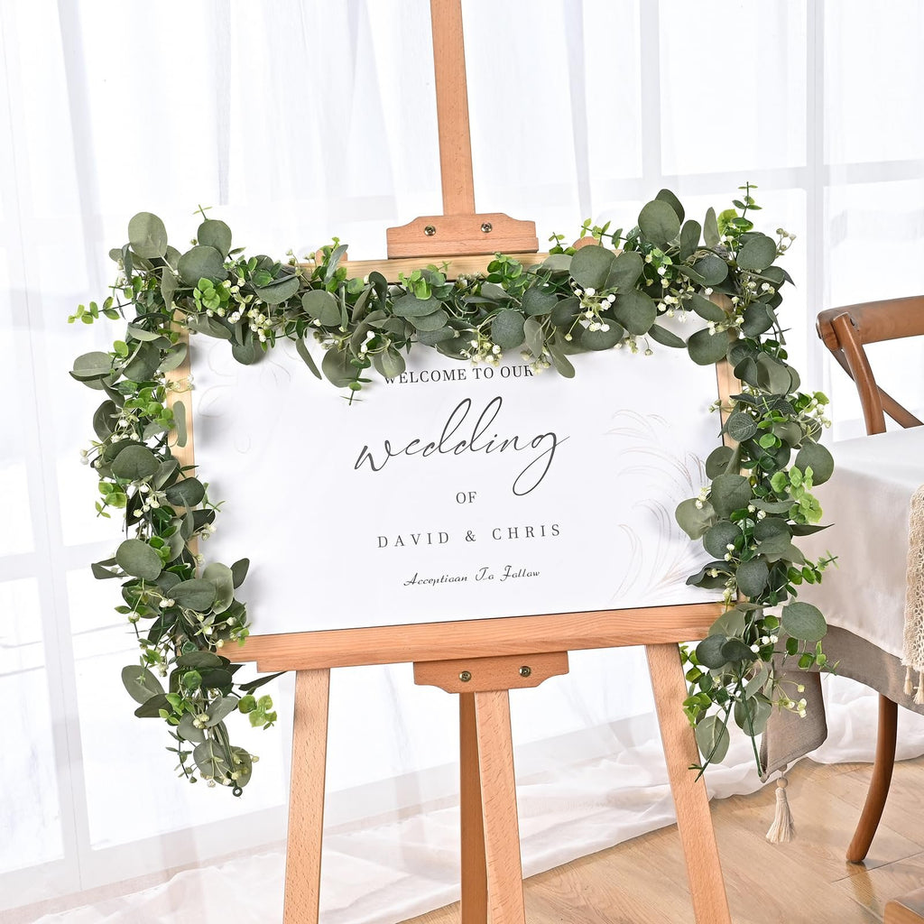 Artificial eucalyptus garland draped around a wedding welcome sign on an easel