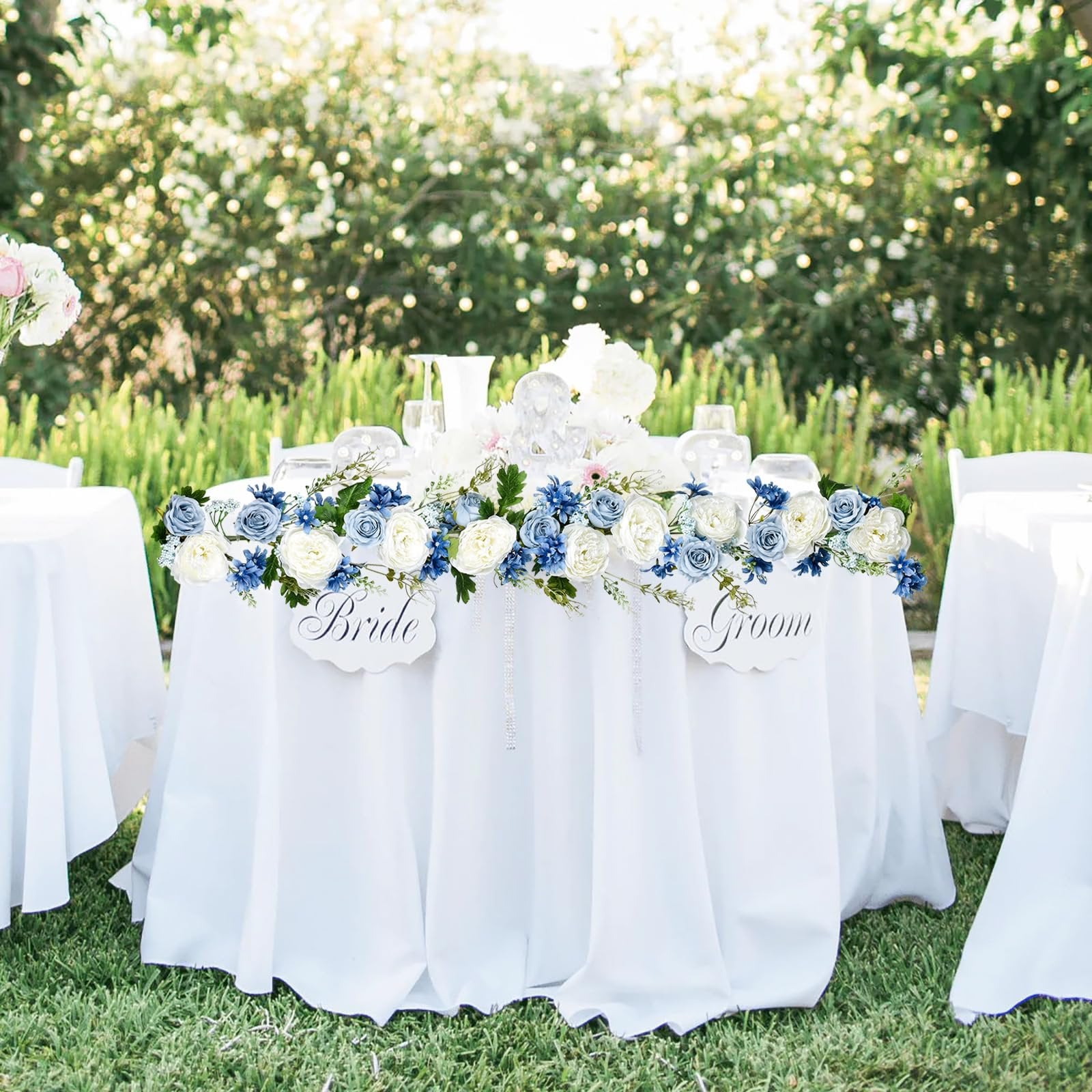 Wedding table decorated with blue and white artificial flower garland, Bride and Groom signs.