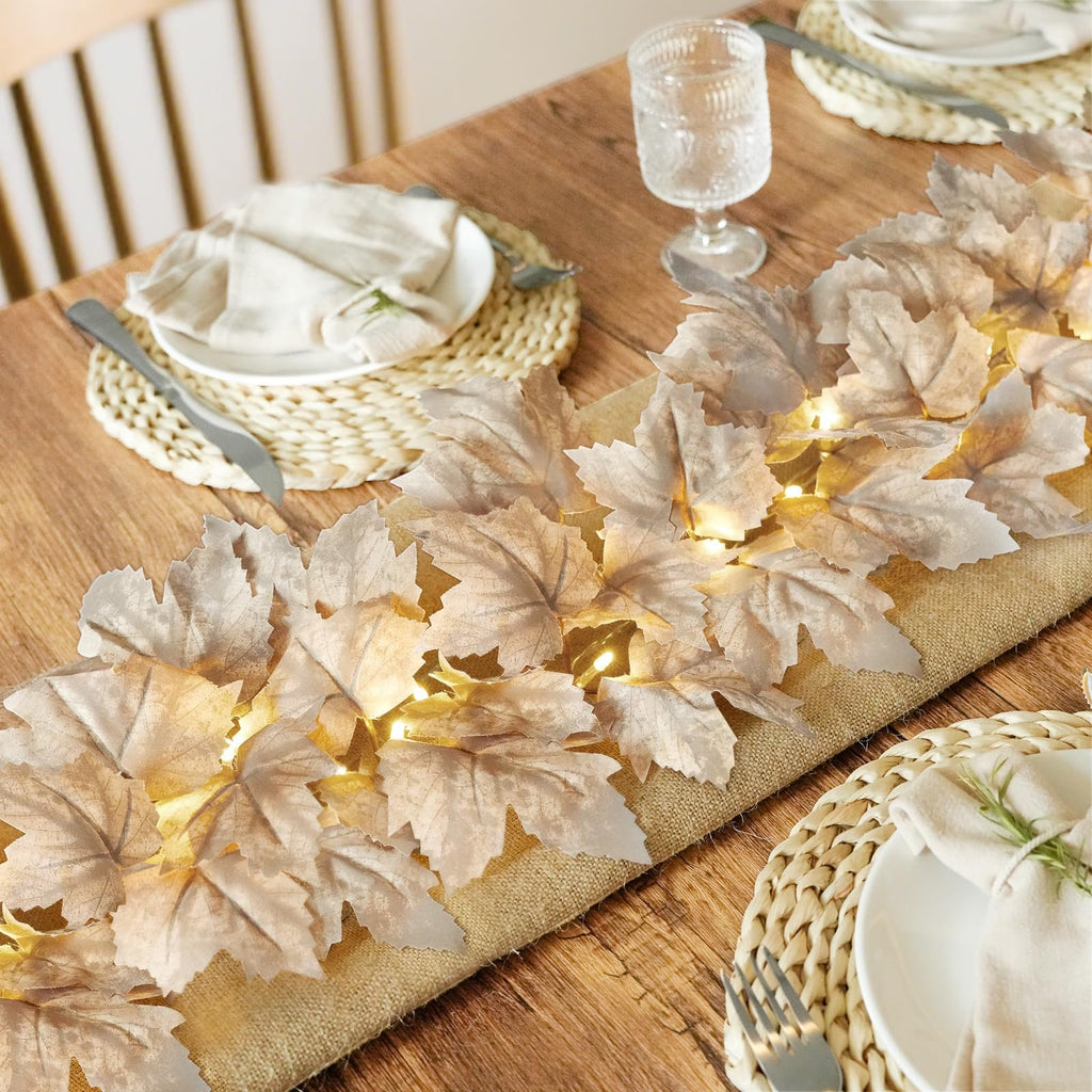 Lighted fall maple leaf garland draped on a wooden table with place settings