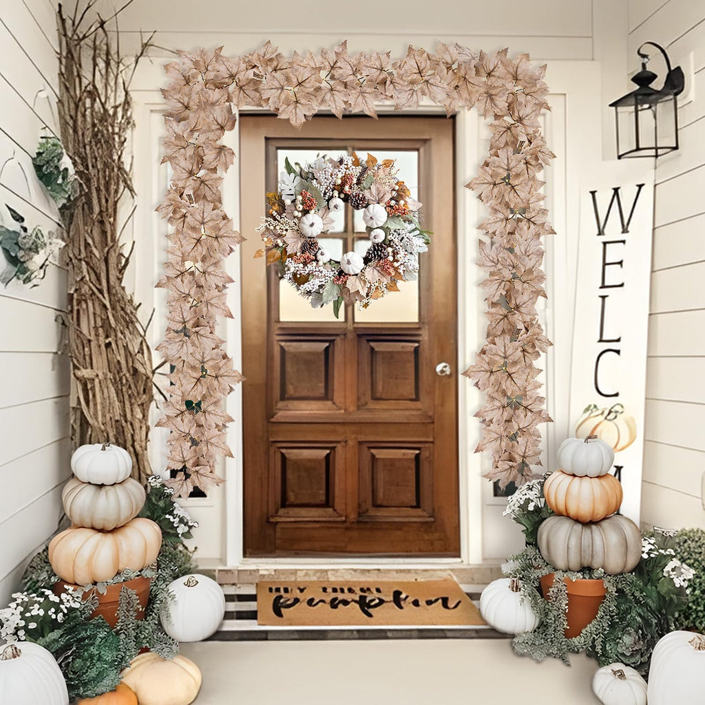 Front door decorated for fall with maple leaf garlands and a wreath, pumpkins, and a welcome sign.
