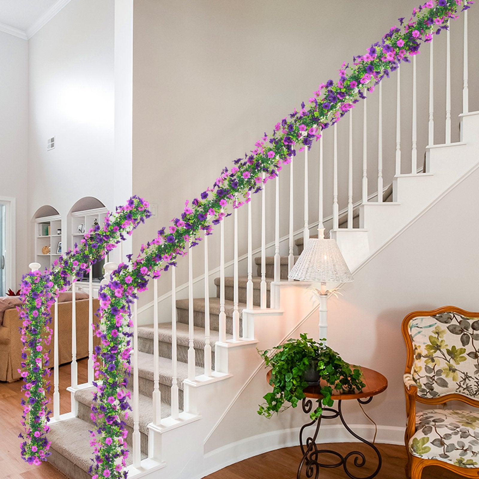 Two artificial daisy flower garlands with purple and pink flowers draped along a white staircase railing.