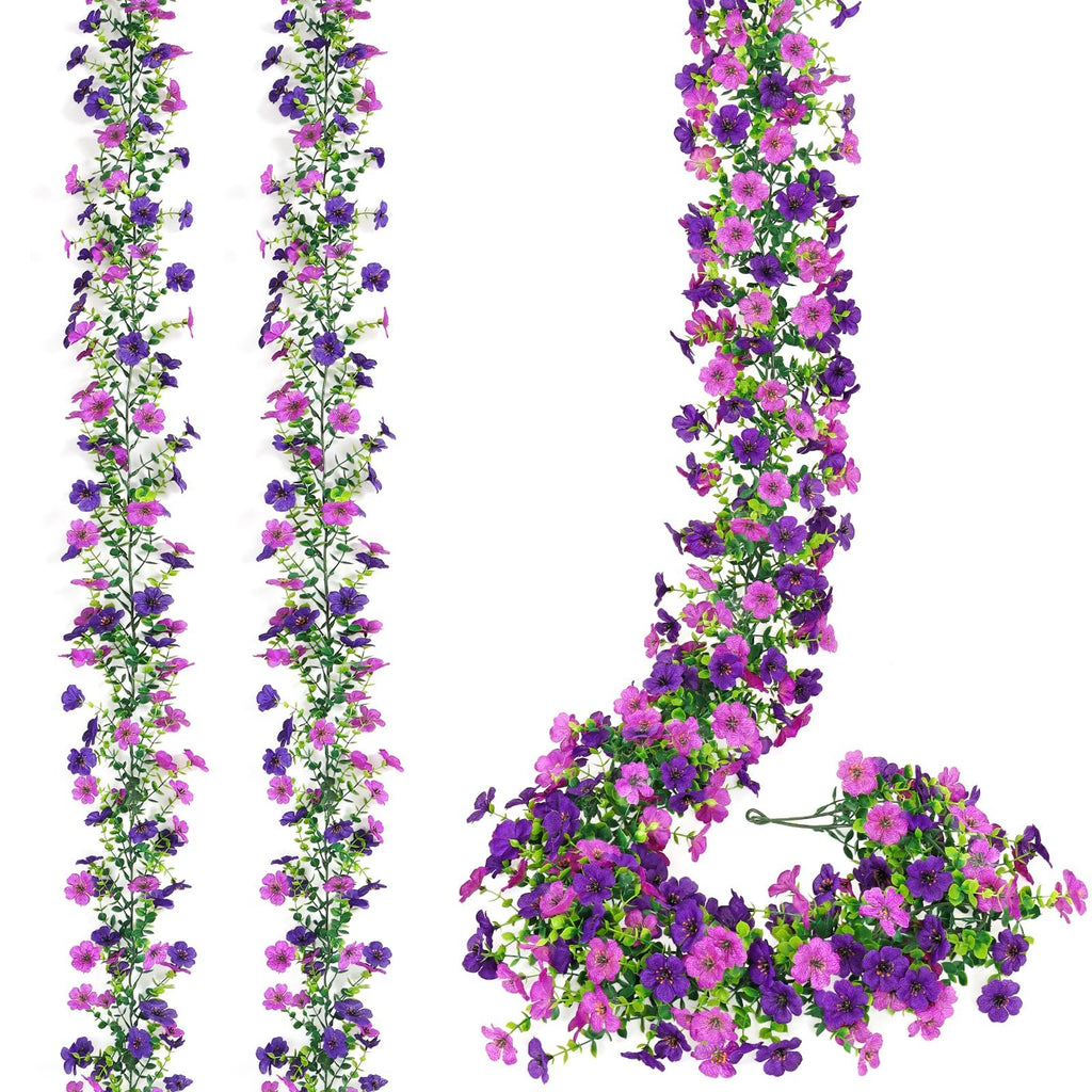 Two artificial daisy flower garlands with purple and pink flowers and green leaves on a white background.