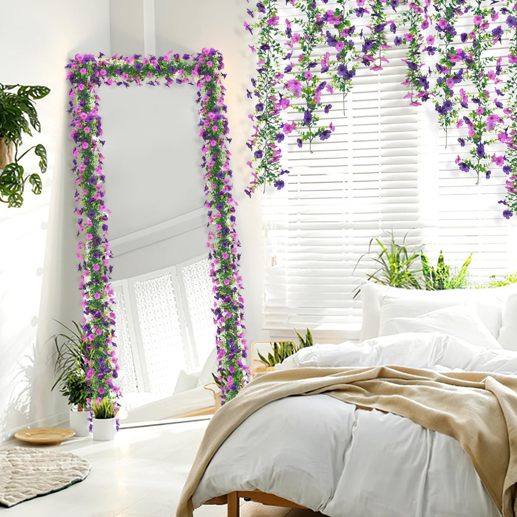 Artificial daisy flower garland with purple and pink flowers draped around a full-length mirror and hanging near a window with blinds.