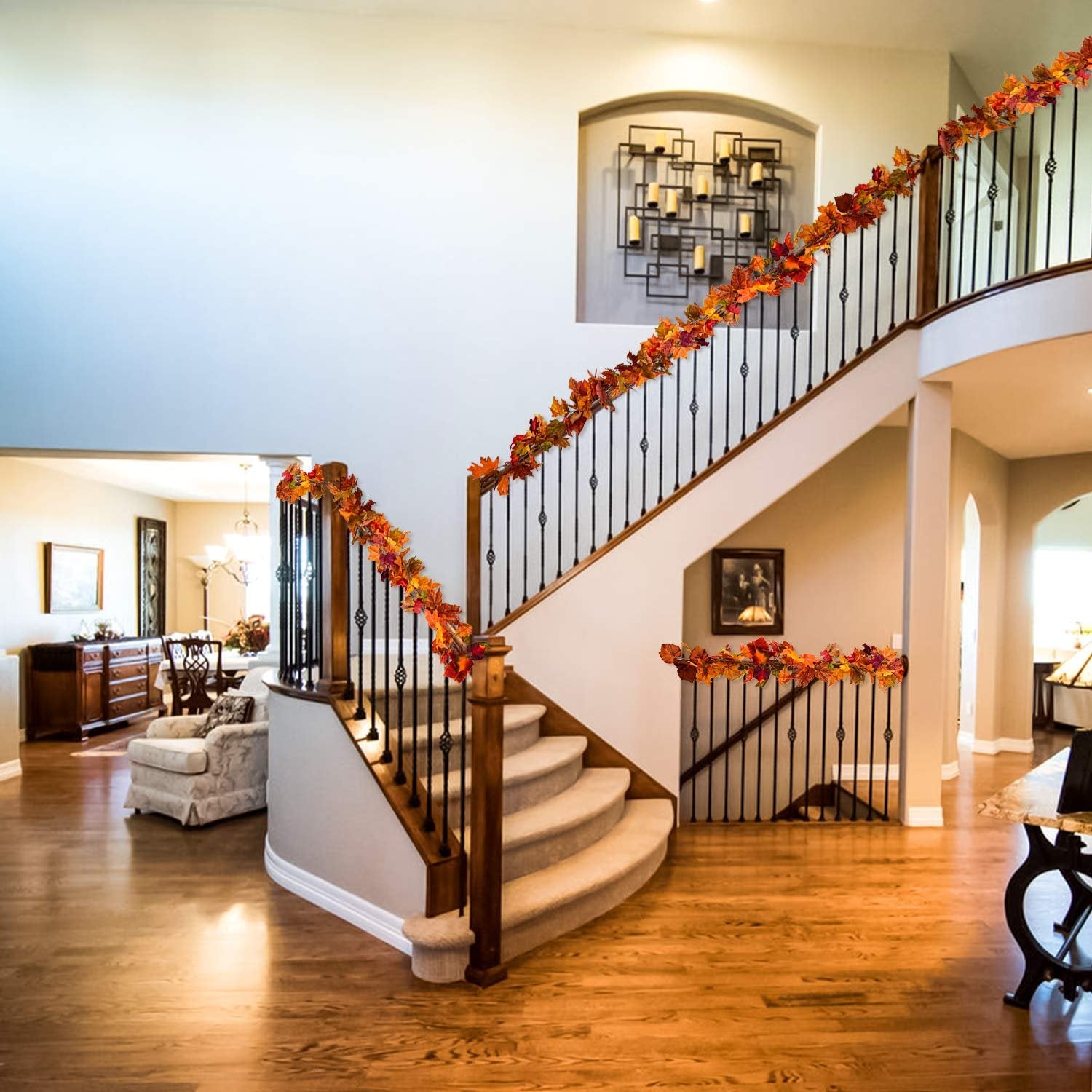 Two artificial fall maple leaf garlands draped along a staircase railing and landing, showcasing autumn colors.