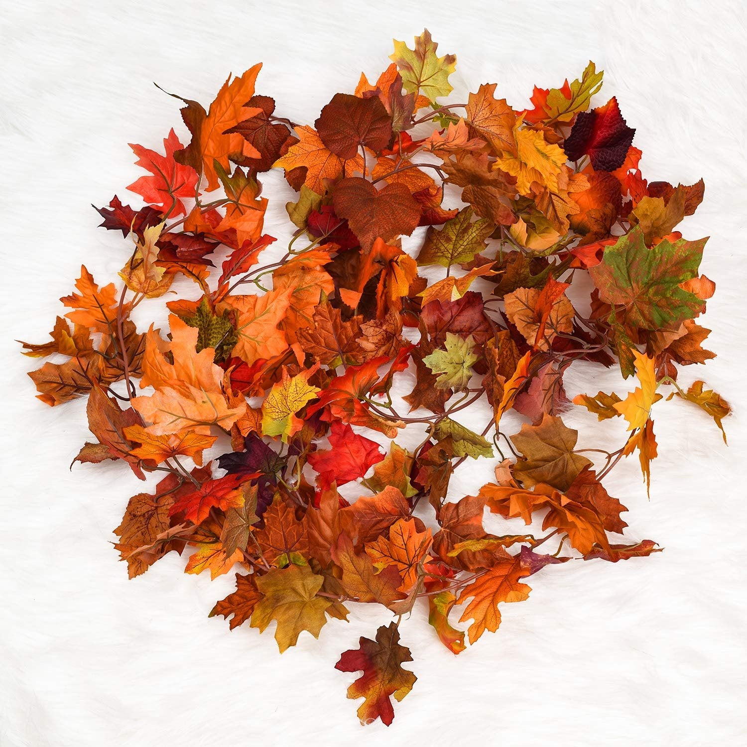Pile of artificial maple leaves in autumn colors on a white fluffy background