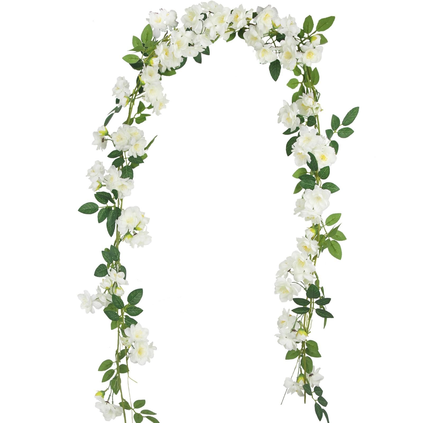 Artificial gardenia garland with white silk flowers and green leaves on a white background, shown draped in an arch shape.