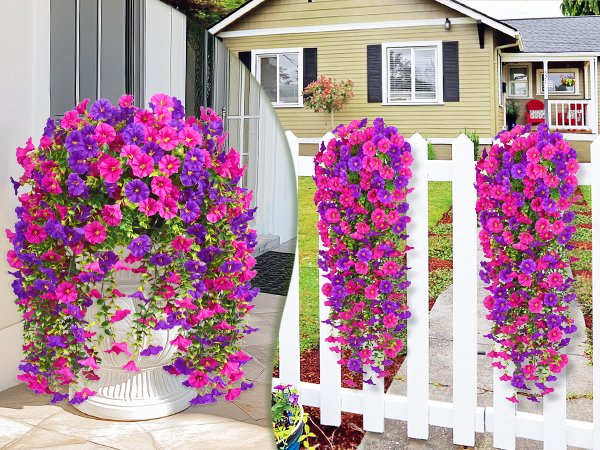 Two hanging baskets of artificial fuchsia and rose red petunia flowers cascading down a white picket fence.