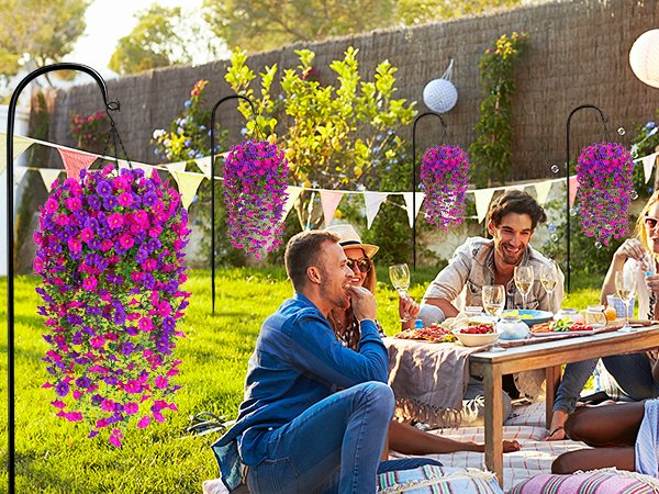 Two hanging baskets of artificial fuchsia and rose red petunia flowers displayed at an outdoor picnic party.