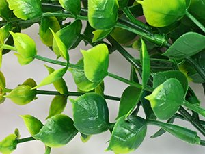 Close-up of artificial hanging petunia flower stems with green leaves and buds against a white background.