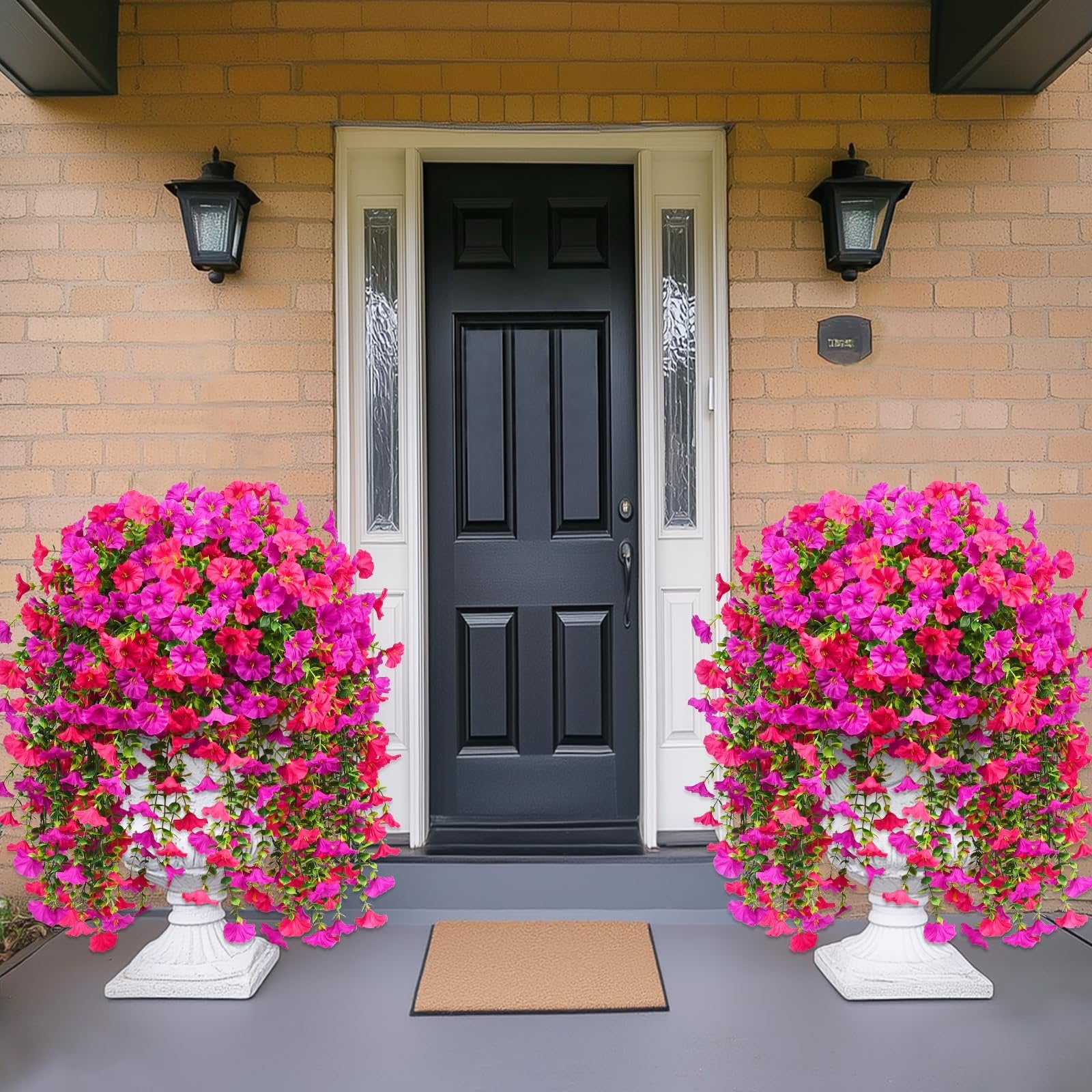 Two large planters filled with vibrant pink and fuchsia artificial petunia flowers flanking a dark front door.
