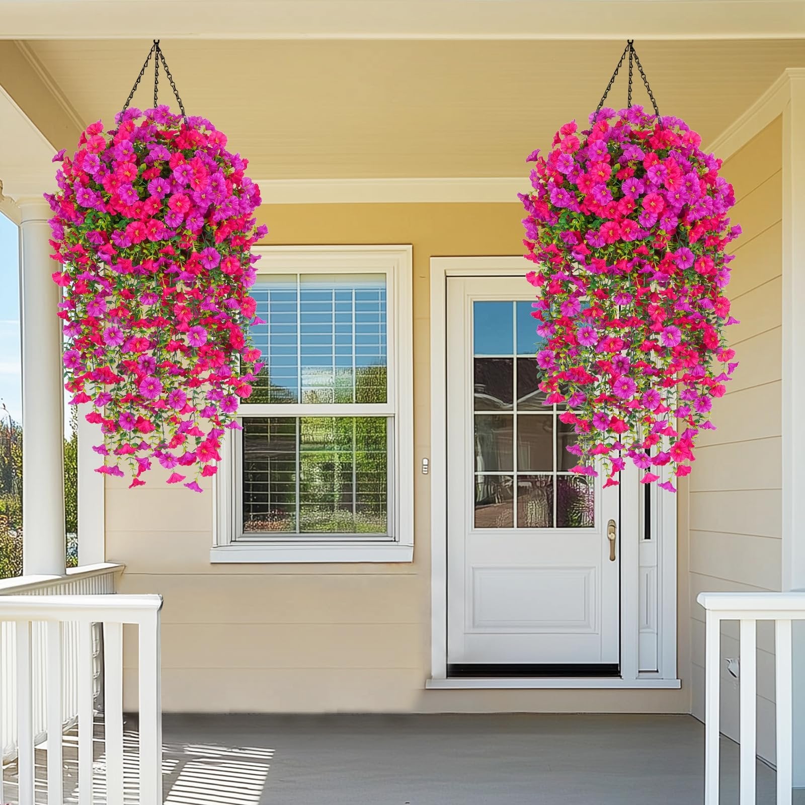 Two hanging baskets of artificial fuchsia and rose red petunia flowers adorn a porch with a window and door.