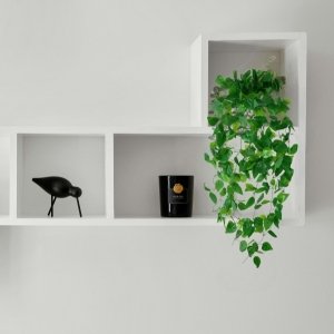 Artificial ivy hanging vine with green leaves cascading from a white shelf