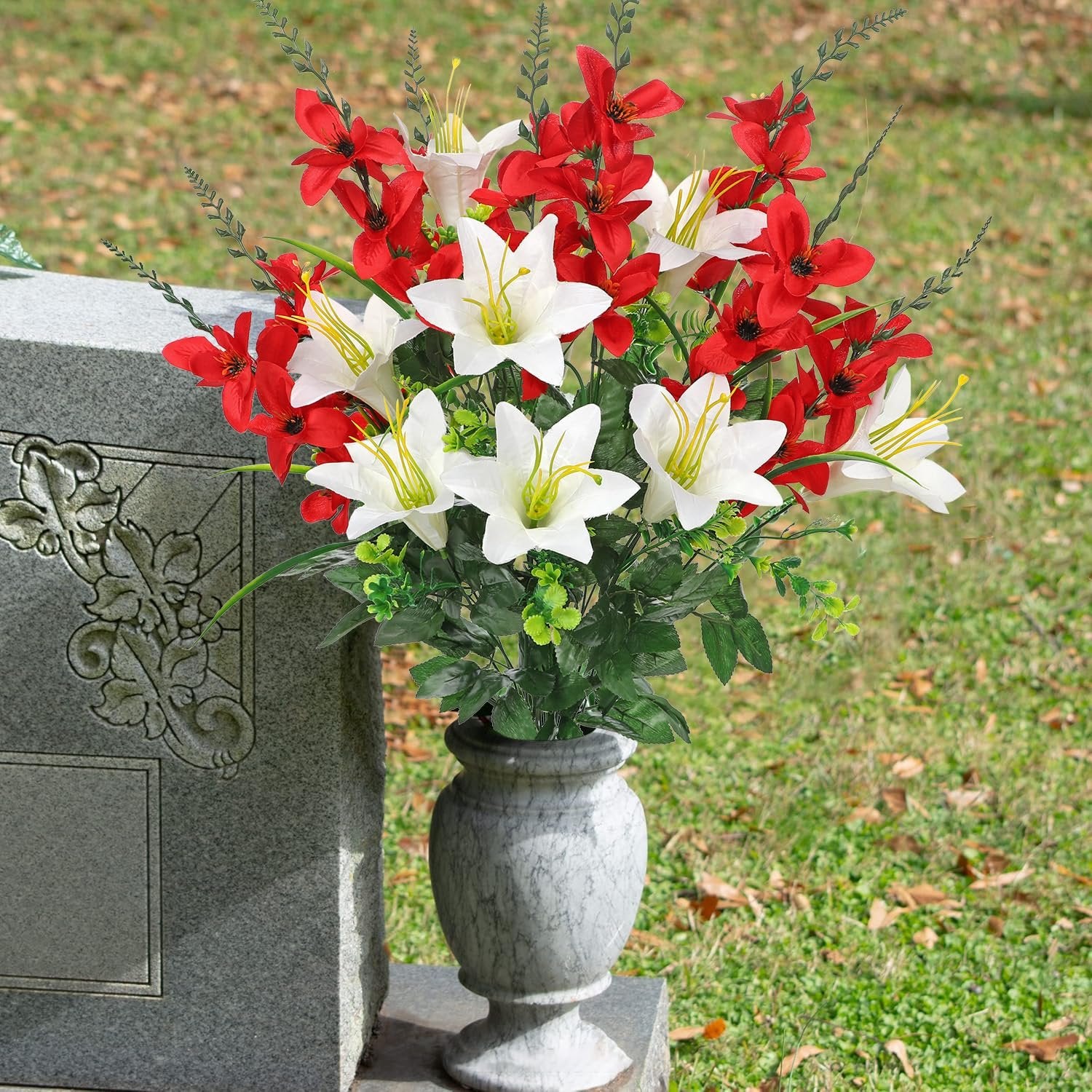 Artificial red and white lily and gladiolus flowers in a vase next to a gravestone