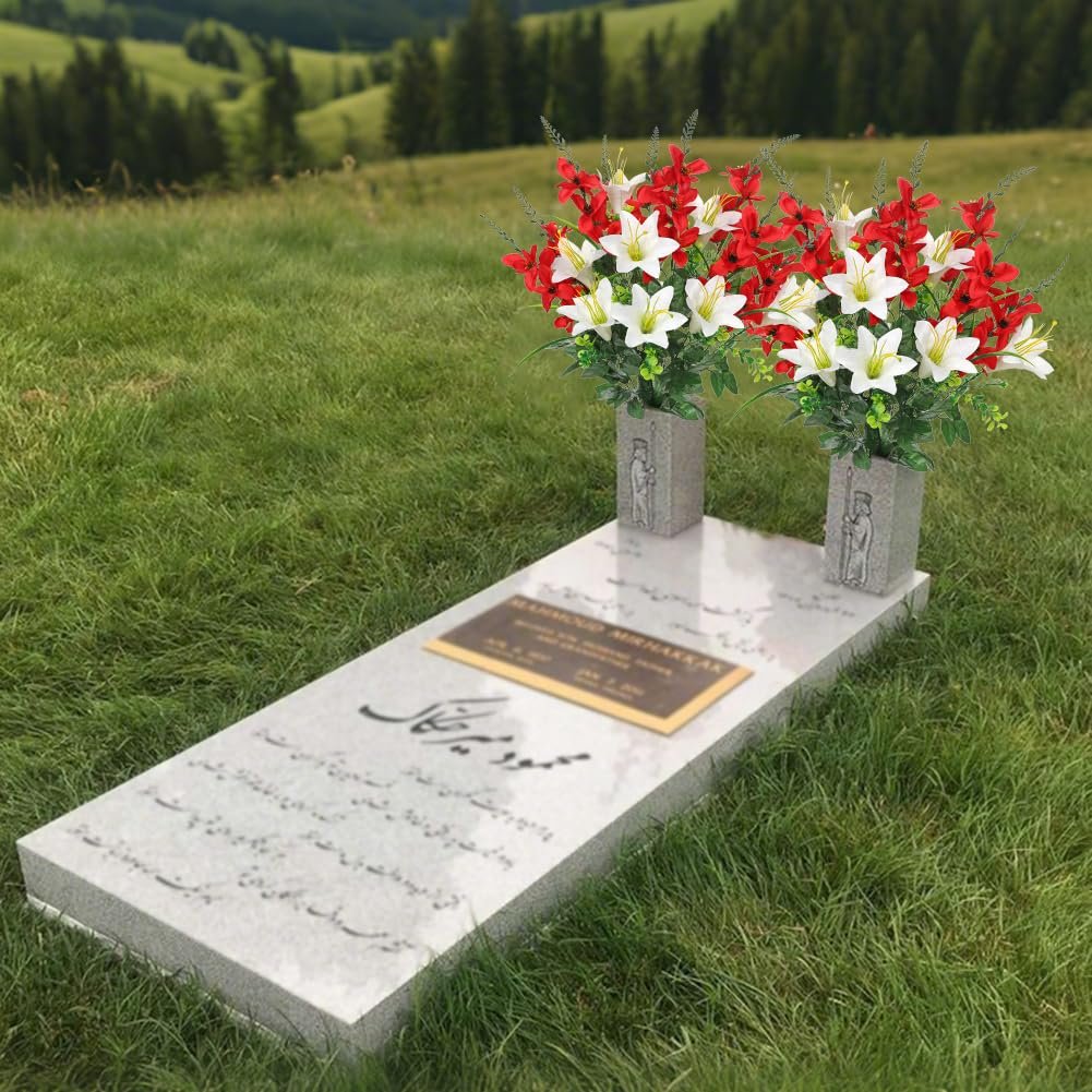 Two artificial flower arrangements with red and white lilies and gladiolus placed on a cemetery headstone.