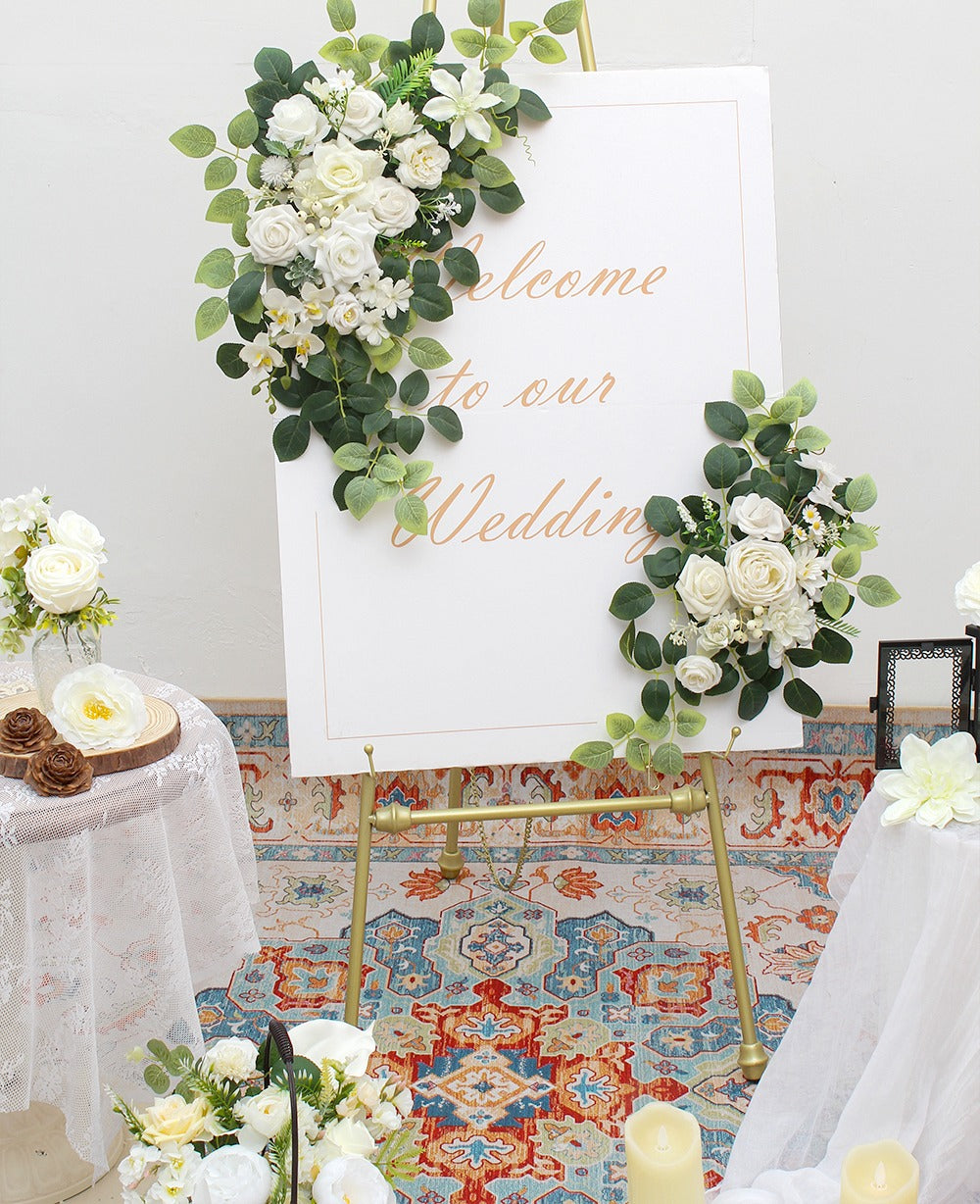 White artificial wedding arch flower garlands draped on a welcome sign easel with text 'Welcome to our Wedding'