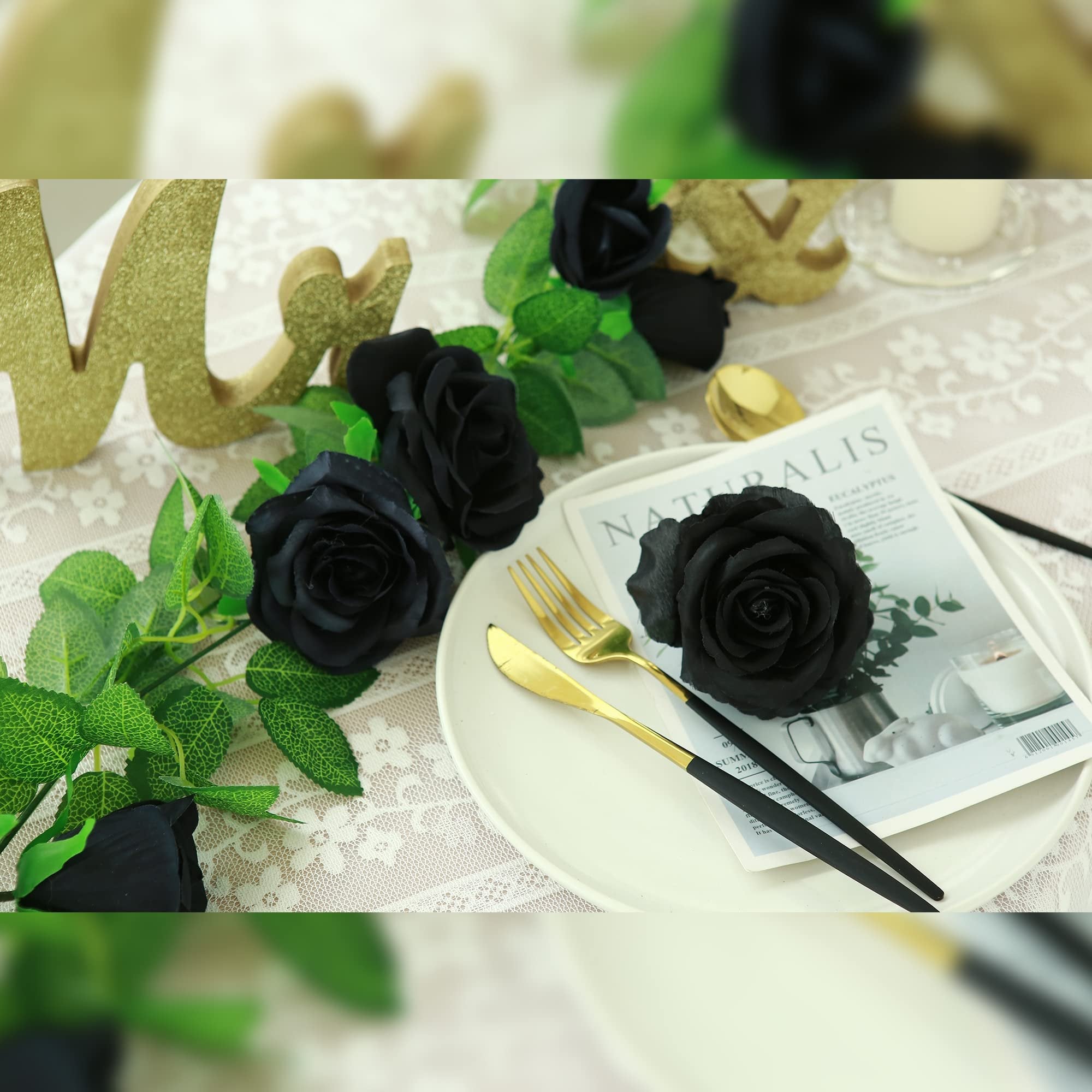 Black artificial rose garland draped across a table setting with gold cutlery and a magazine.