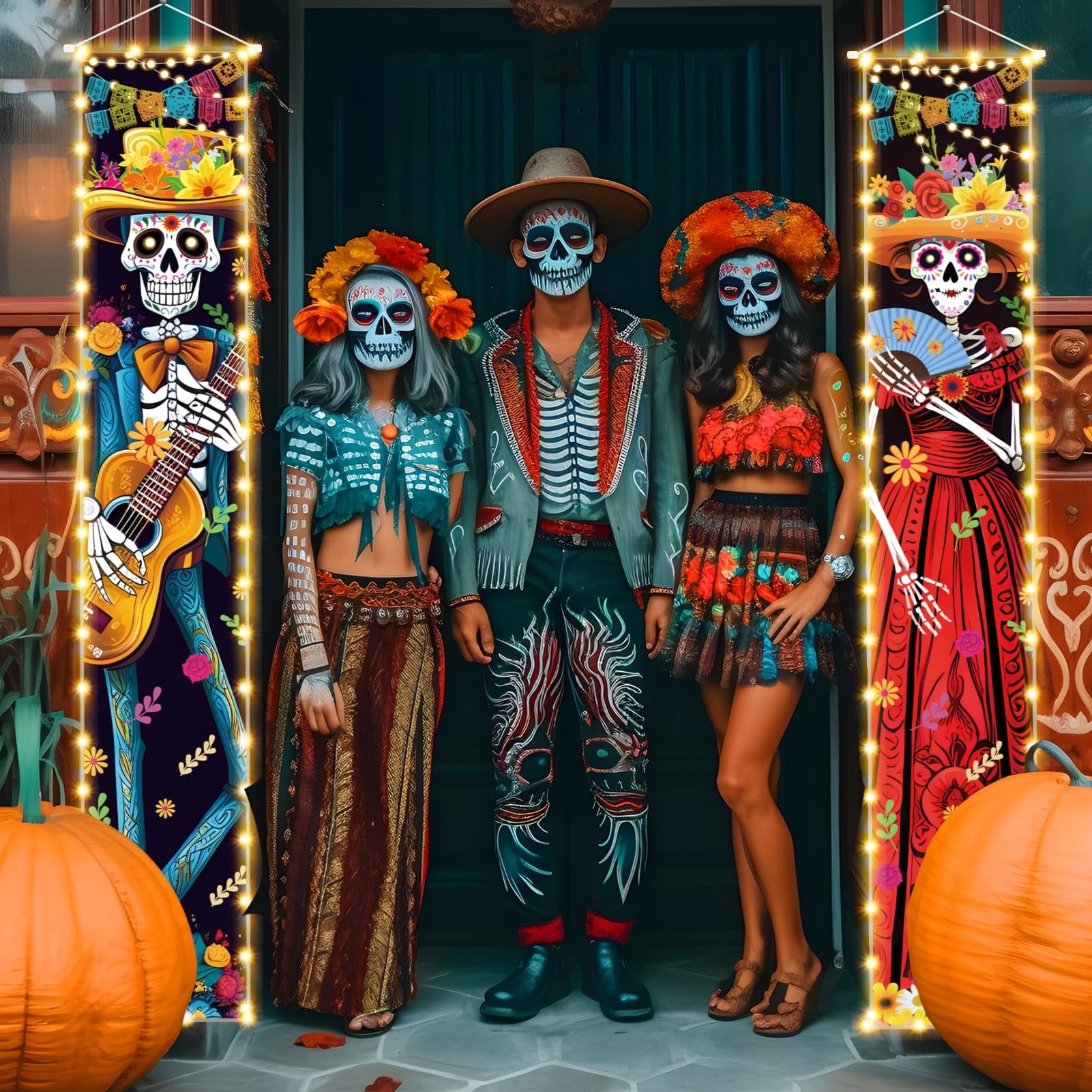 Three people in Dia de los Muertos costumes stand between two lighted porch sign banners featuring skeleton figures and pumpkins.