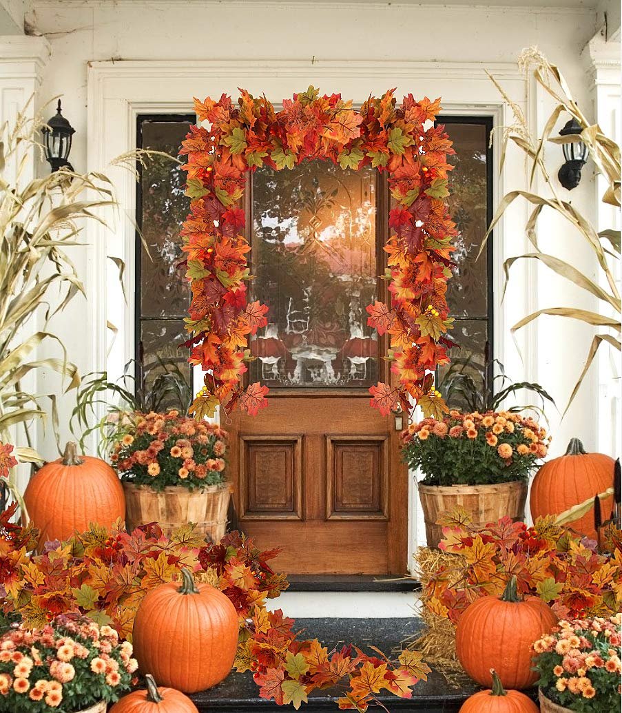 Autumn maple leaf garland and pumpkins decorating a front porch entrance.