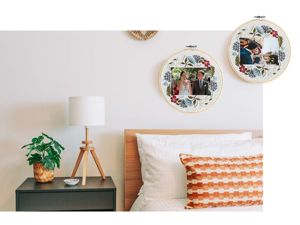 Two floral embroidery photo frames with wedding photos displayed on a bedroom wall above a nightstand.