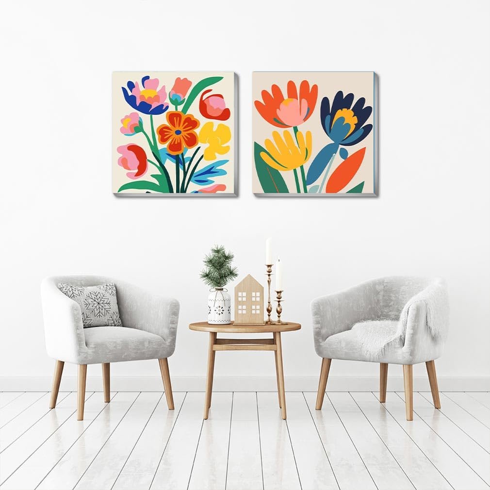 Two framed floral paintings displayed on a white wall above two armchairs and a side table.