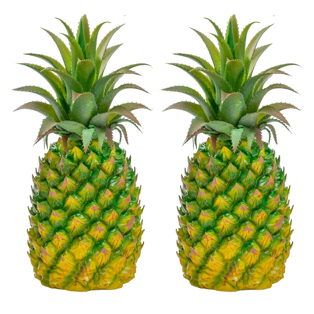 Two artificial green pineapples with textured yellow and green bodies and spiky green leaves, isolated on a white background.