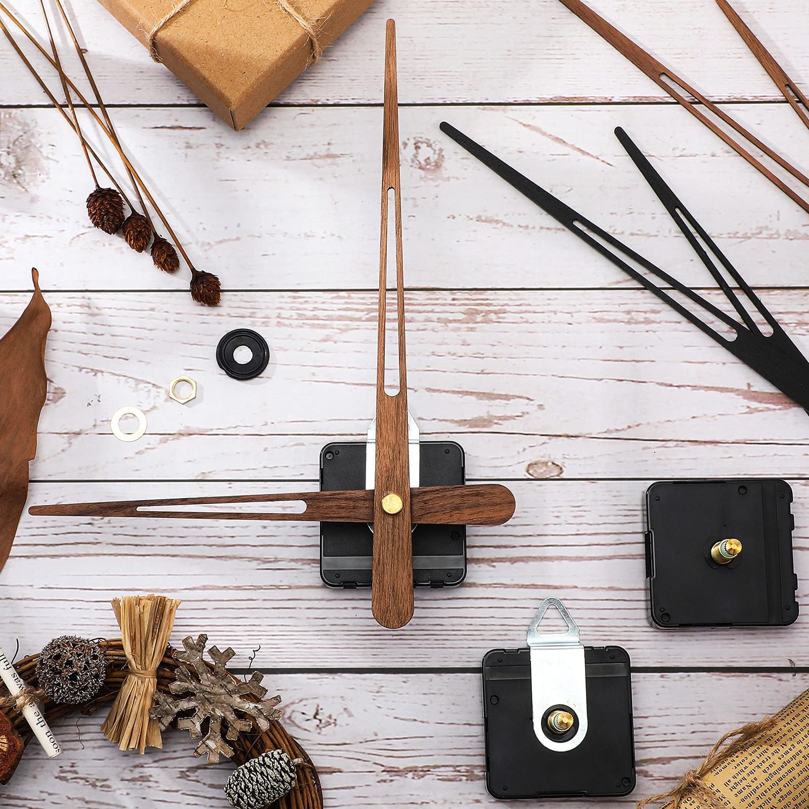 Clock movement mechanisms and walnut wood clock hands laid out on a wooden surface with decorative elements.