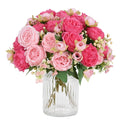 Mixed pink silk peonies in a clear glass vase, front view. Bouquet features large peony blooms and smaller buds.