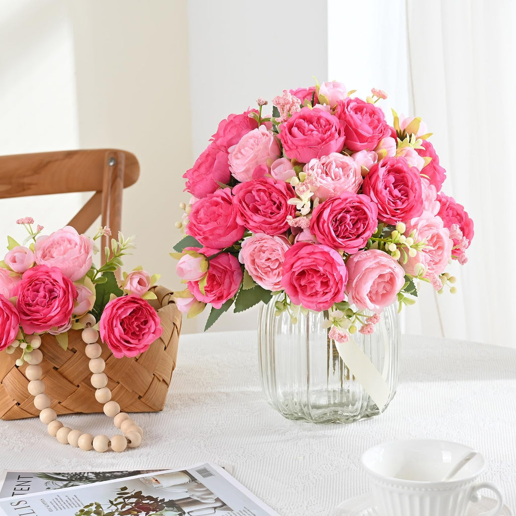 Two bouquets of pink silk peonies, one in a glass vase and one in a woven basket with wooden beads.