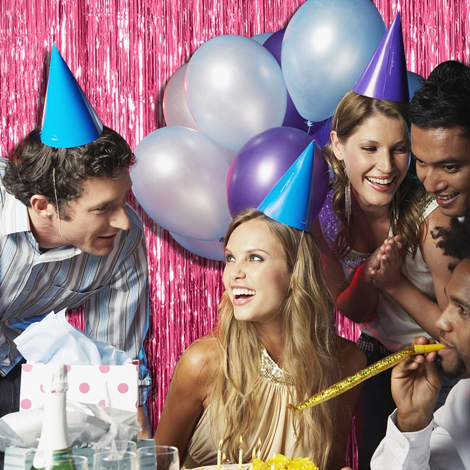 Group of people celebrating with party hats and balloons, with a pink tinsel backdrop.