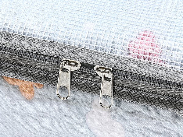 Close-up of two zippers on a clear under-bed storage container with a patterned fabric.