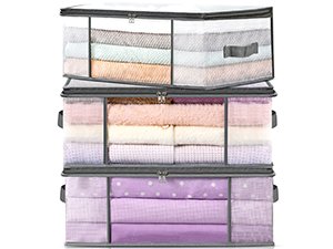 Three stacked clear plastic under-bed storage containers with handles, filled with folded linens and blankets.