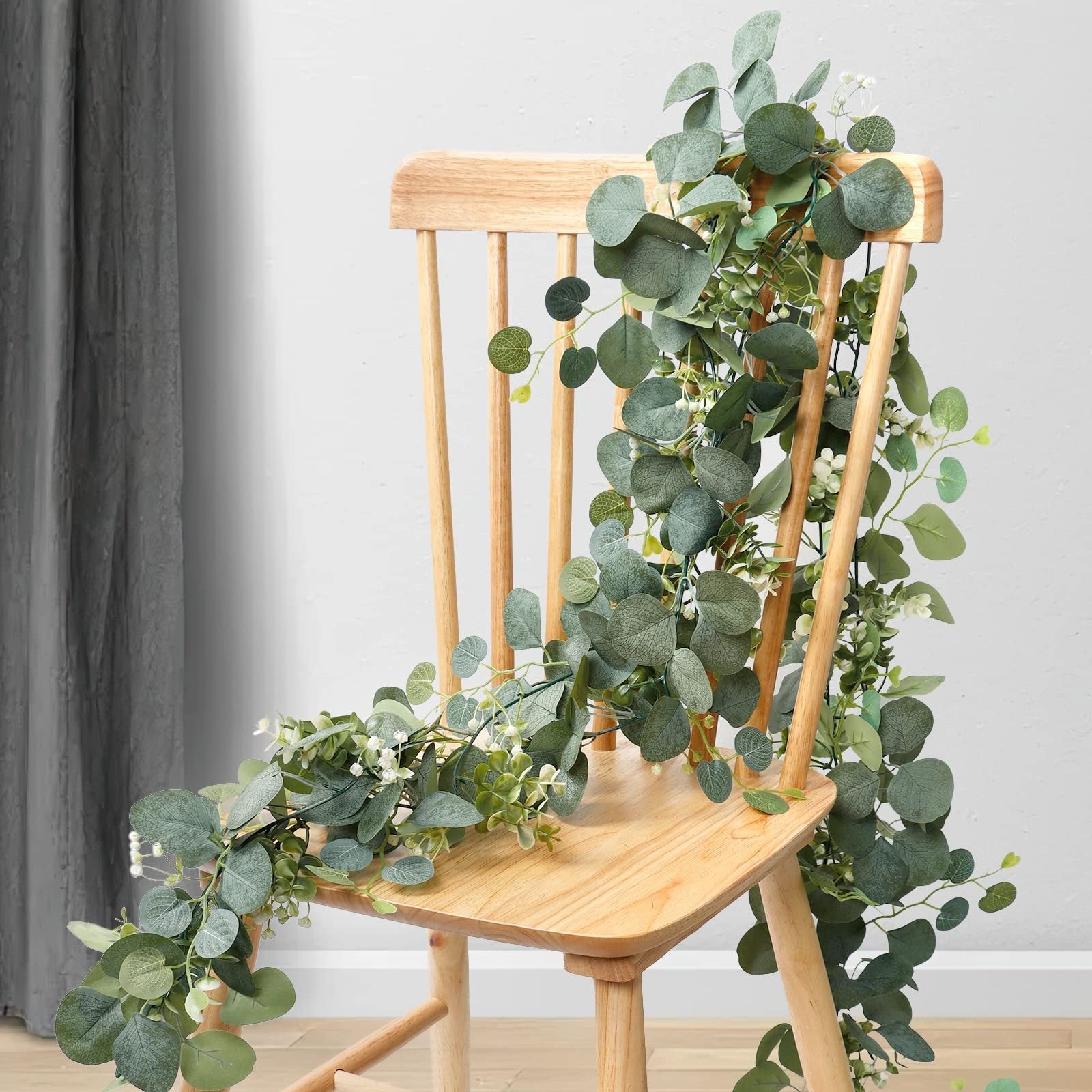 Artificial eucalyptus garland with silver dollar, boxwood, and white flowers draped over a wooden chair.