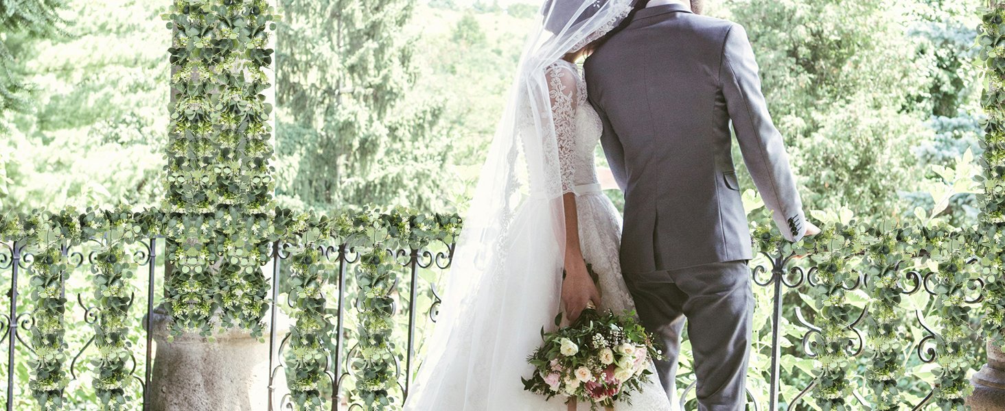 Bride and groom on a balcony draped with artificial eucalyptus and rose garland
