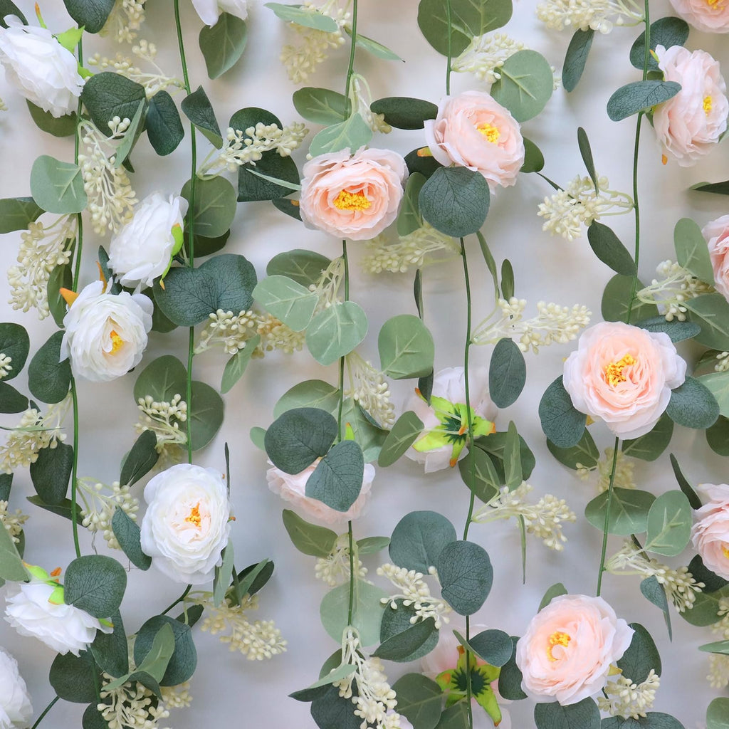 Artificial eucalyptus garland with pink and white roses and seeded leaves against a white background.